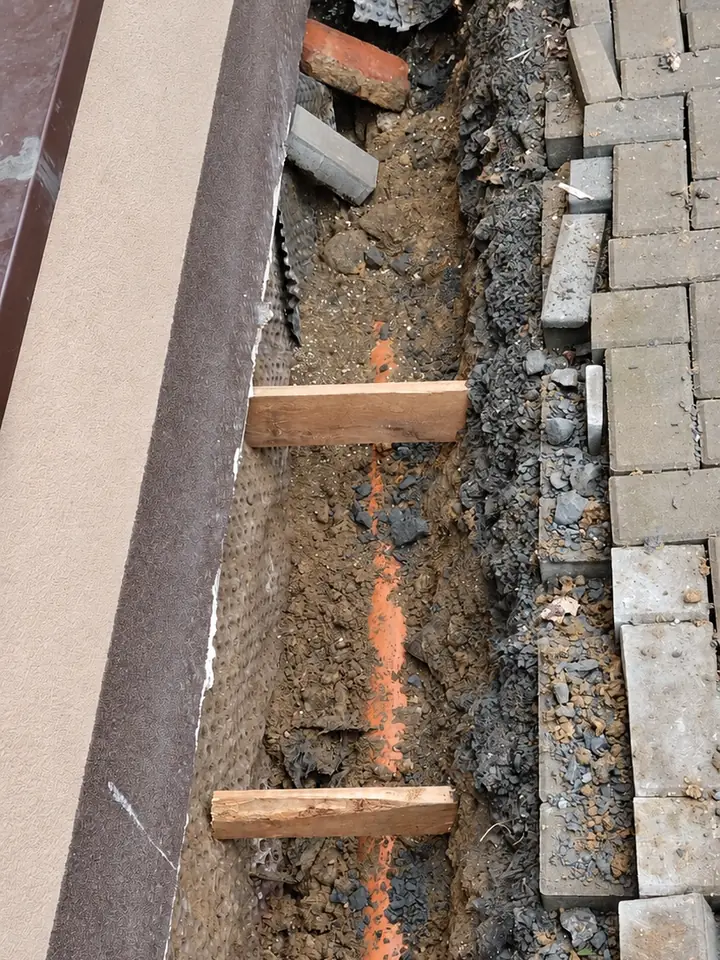 Pohled shora na rýhu u základů domu s potrubím a nopovou fólií