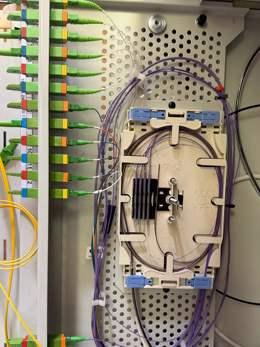 Patch panel se zelenými optickými konektory a kazetou svarů s fialovými vlákny